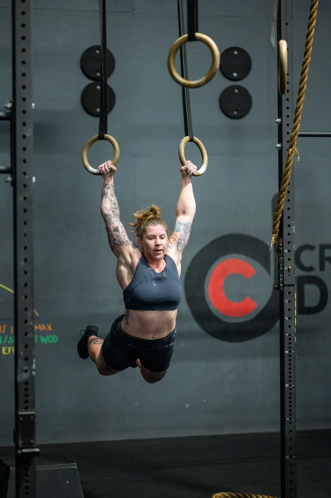 A member on the rings in front of the CrossFit Diligence logo