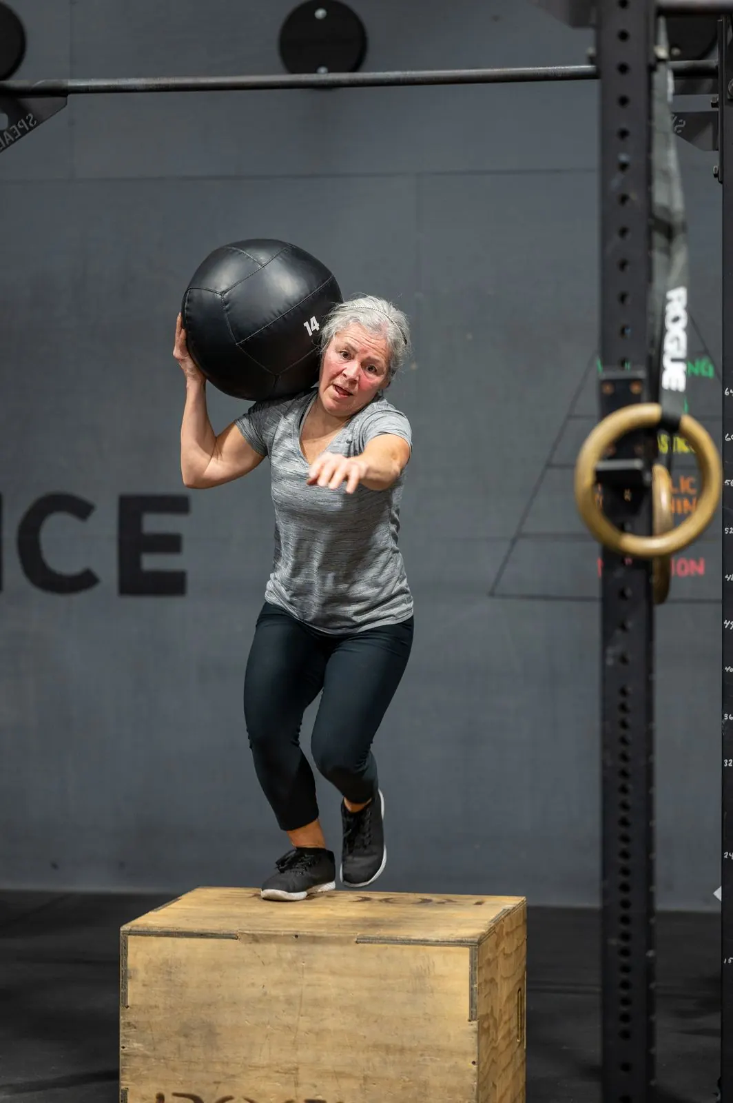 A member stepping down from a box with a 14 pound ball on her shoulder